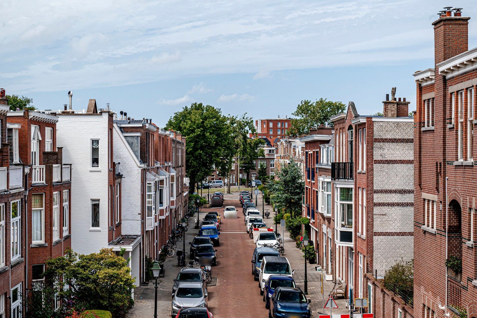 Straat met bakstenen woningen en geparkeerde auto's, overdag — de originele foto.